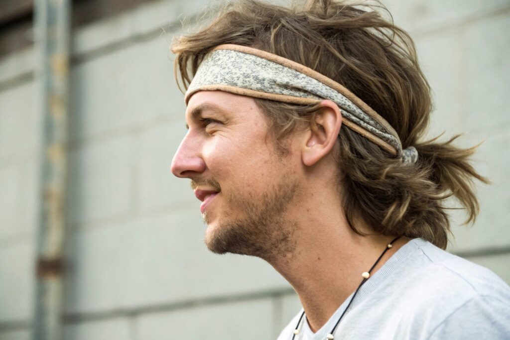 A man with long brown hair wearing a gray headband