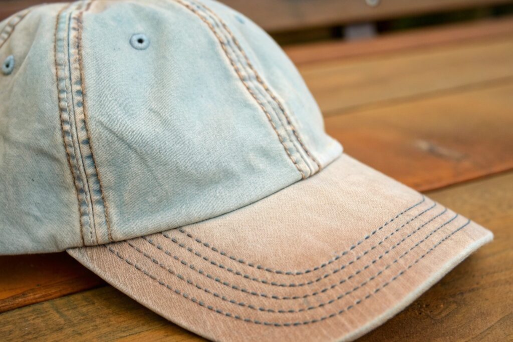 Close-up macro image of a pigment-dyed unstructured dad hat with distressed detailing – Ideal for showcasing vintage-style custom caps, soft washed cotton headwear, or outdoor lifestyle fashion accessories.