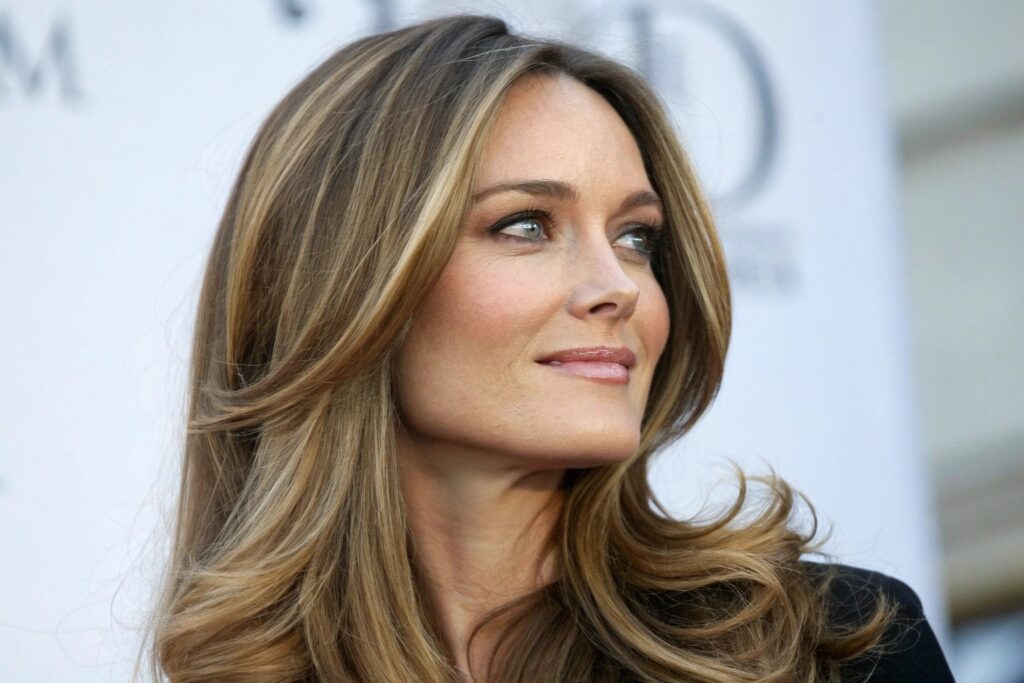 A person with long, wavy brown hair with blonde highlights looking to the right