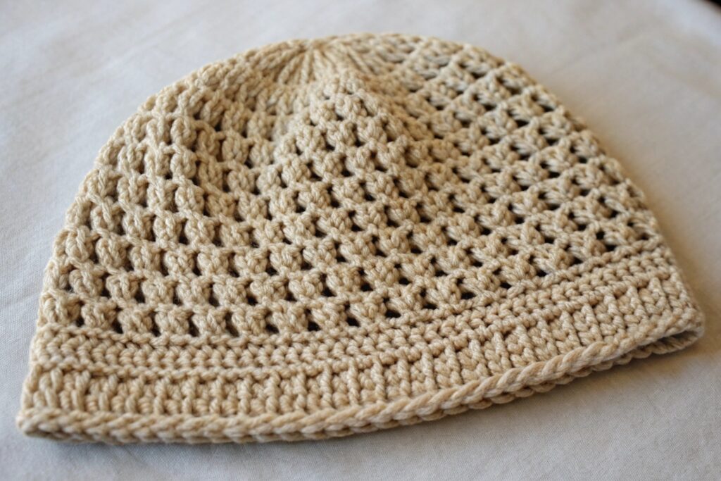 A beige crochet beanie hat on a white surface