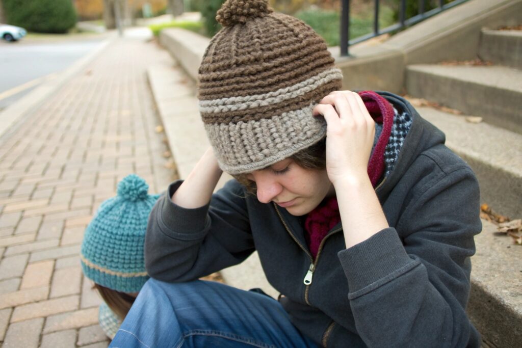 A person wearing a brown knit hat on a sidewalk