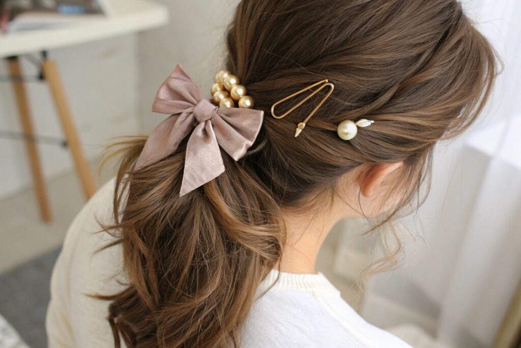 A woman with long brown hair wearing a pink bow and pearl hair accessories