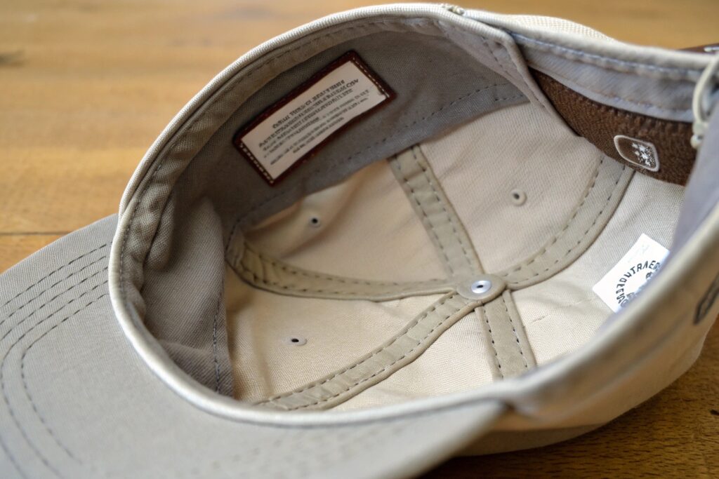 A blue-gray baseball cap with white embroidery that says "DAD HAT" and a crest-like design
