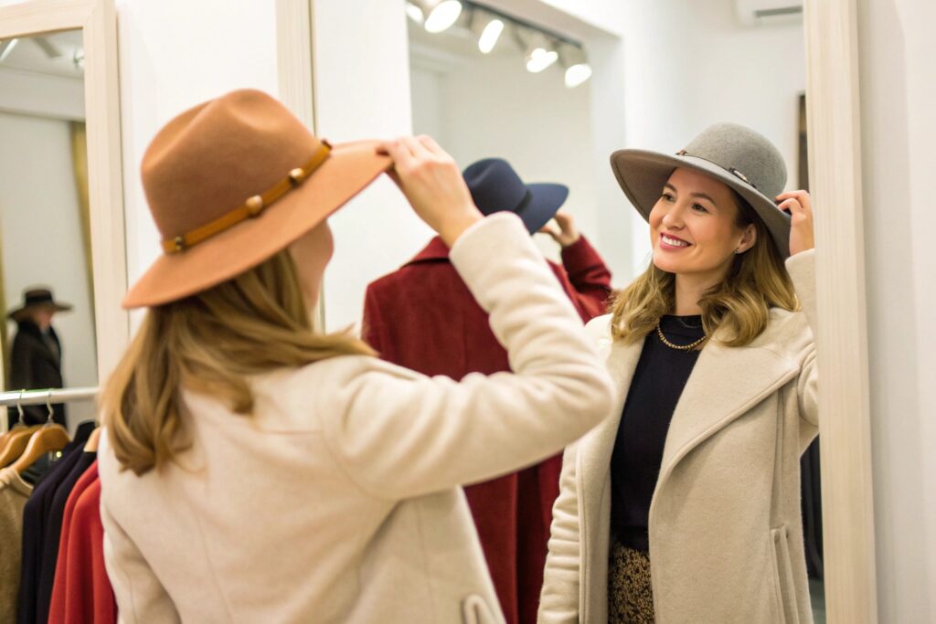 Two people trying on hats in front of a mirror in a clothing store